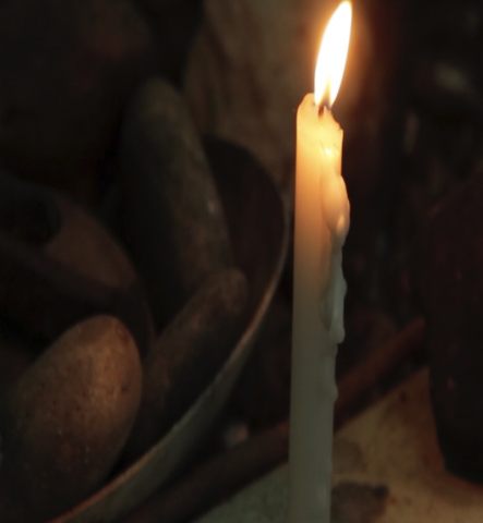 photo of a candle flame shedding dim light on a bowl of potatoes